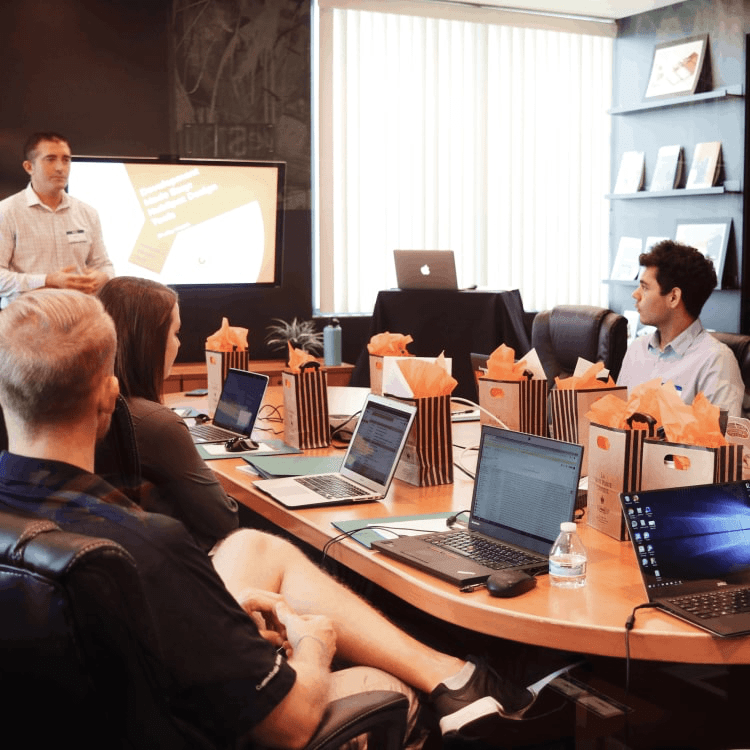 Man presenting to a group of people in a conference room.