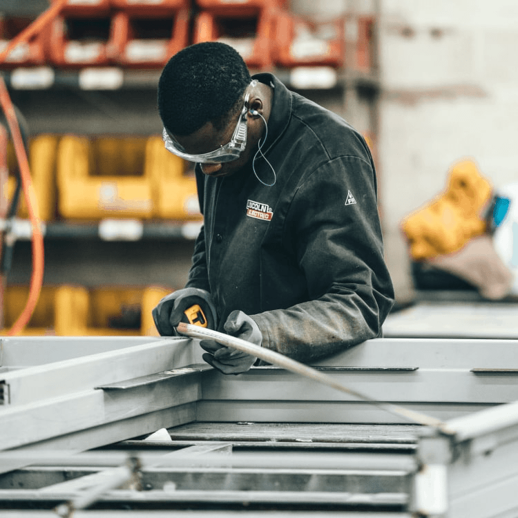 A man working in a factory measuring a length of a material.