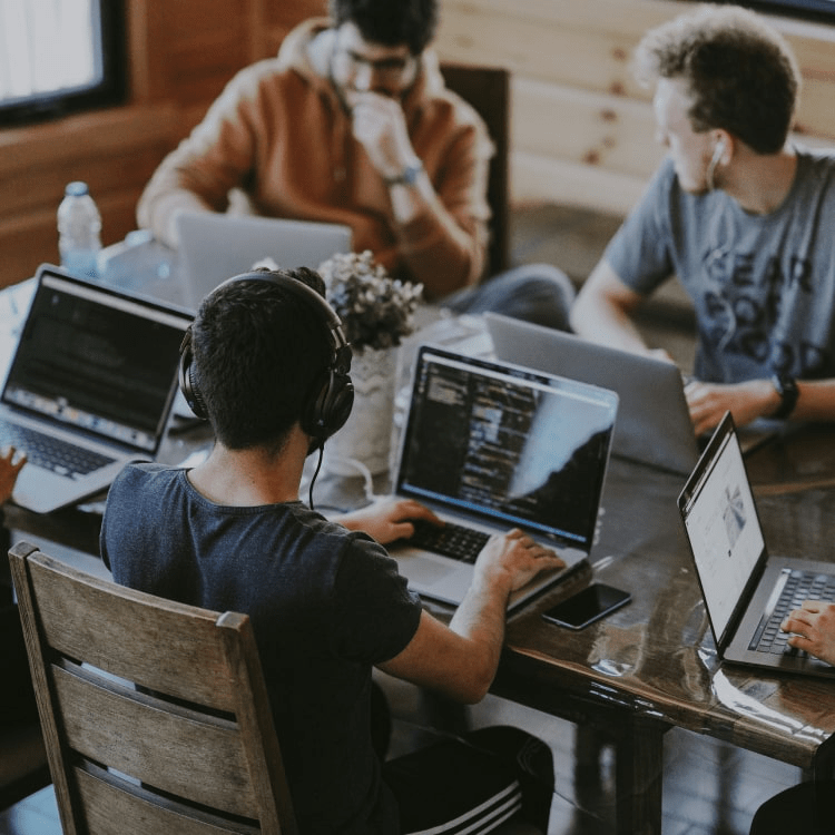 A group of men working on their computers by a table.